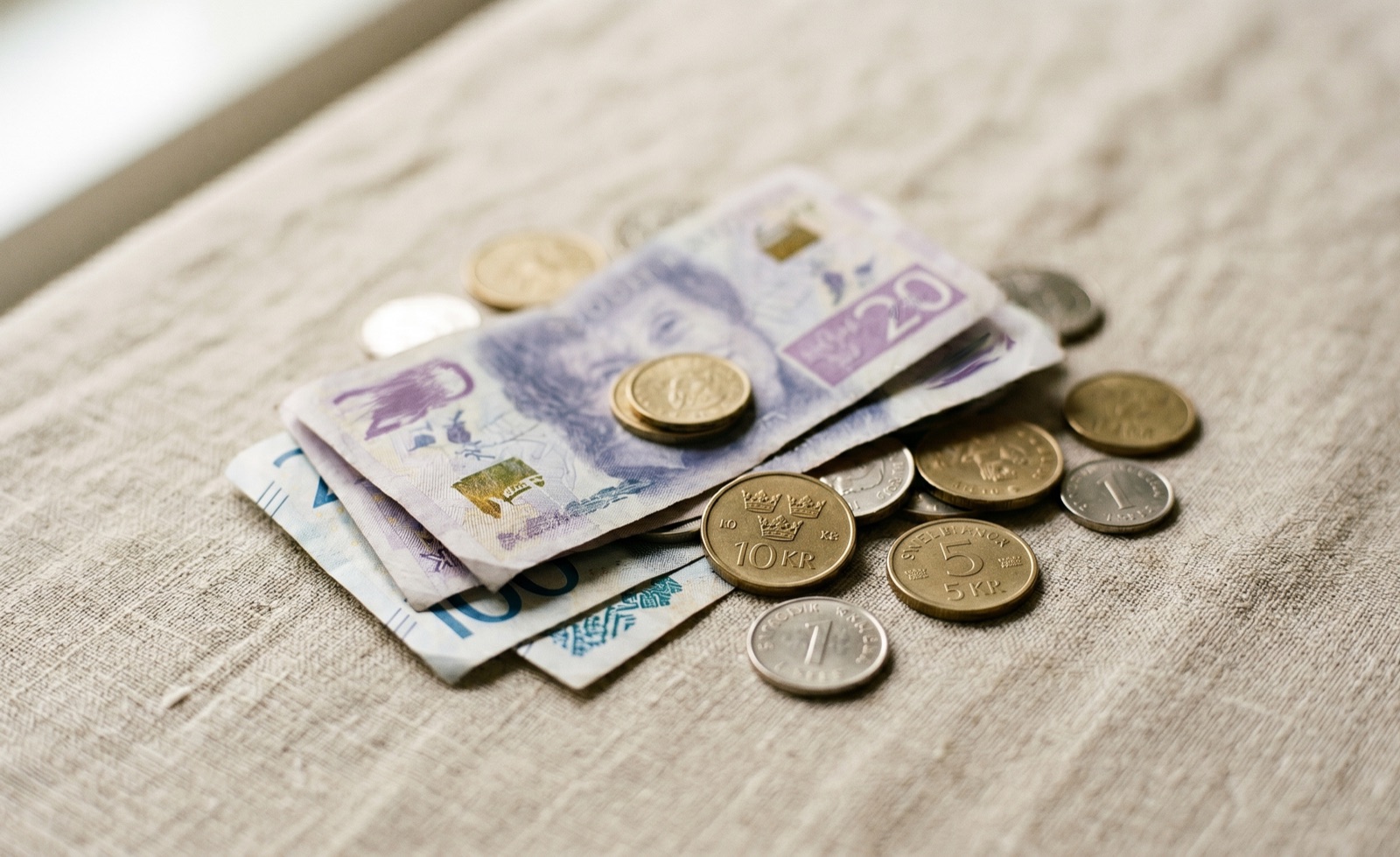 Svenska sedlar och mynt på ett linneunderlag